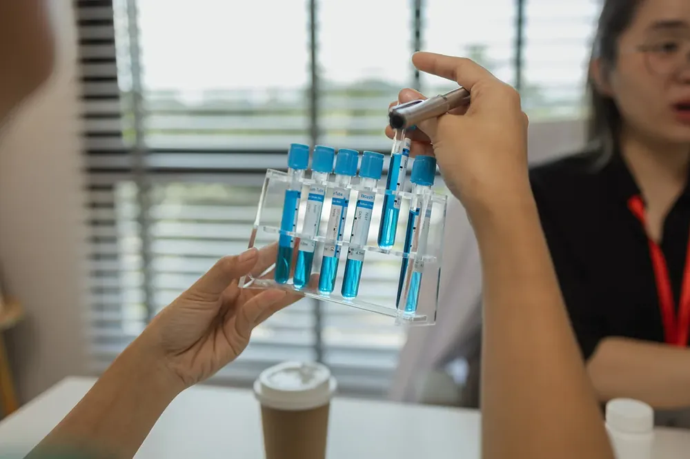 A scientist holds a rack of peptide tubes with blue liquid inside, inside a lab